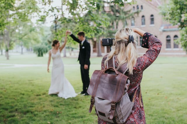 Camera operator filming a bride and groom dancing on a lawn
